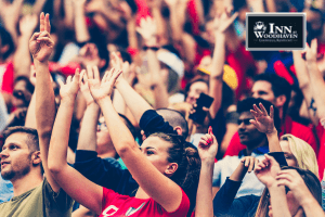 Crowd of adults in mostly red shirts holding their hands up to cheer at an event.