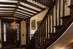 Entry hall with wooden beams on ceiing and ornate staircase.