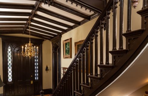 Entry hall with wooden beams on ceiing and ornate staircase.