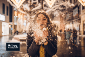 Young adult woman with brown hair is blowing snow out of her hands