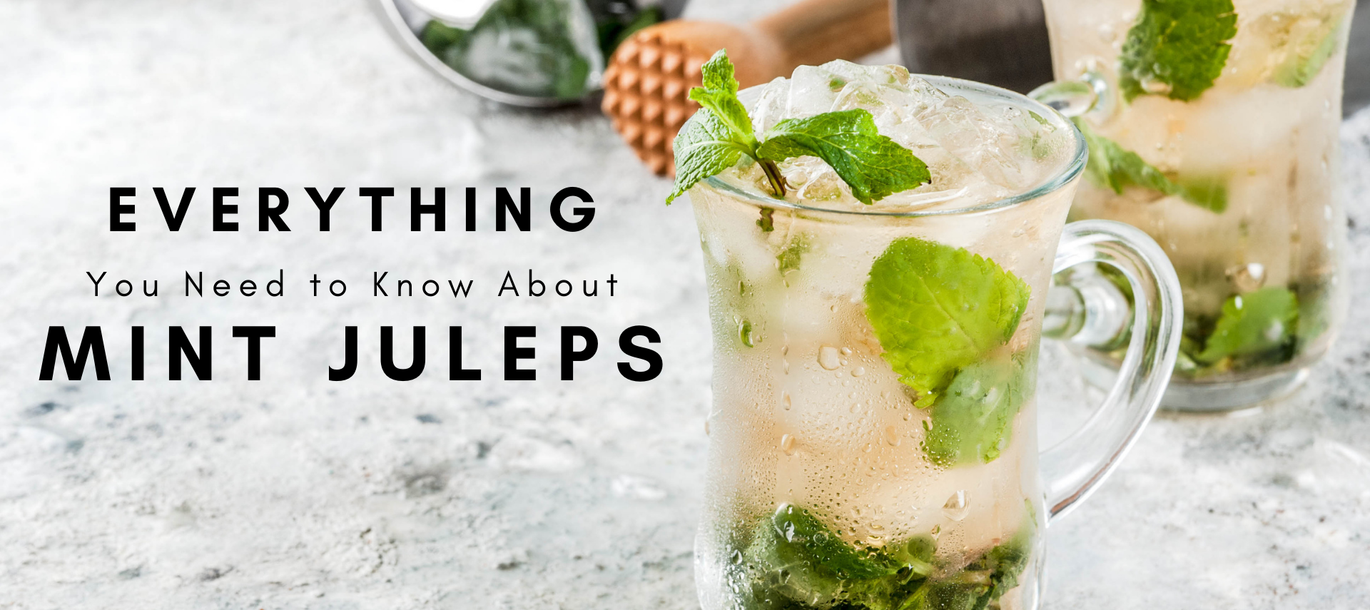 Clear glass filled with ice, mint leaves, and bourbon on a grey marble countertop.