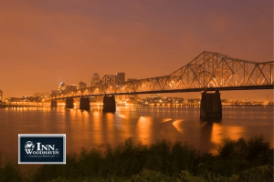 Orange-hued photo of the Louisville Kentucky skyline and bridge across the river at night
