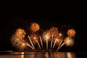 Rainbow fireworks exploding at night and reflecting on the Ohio river.