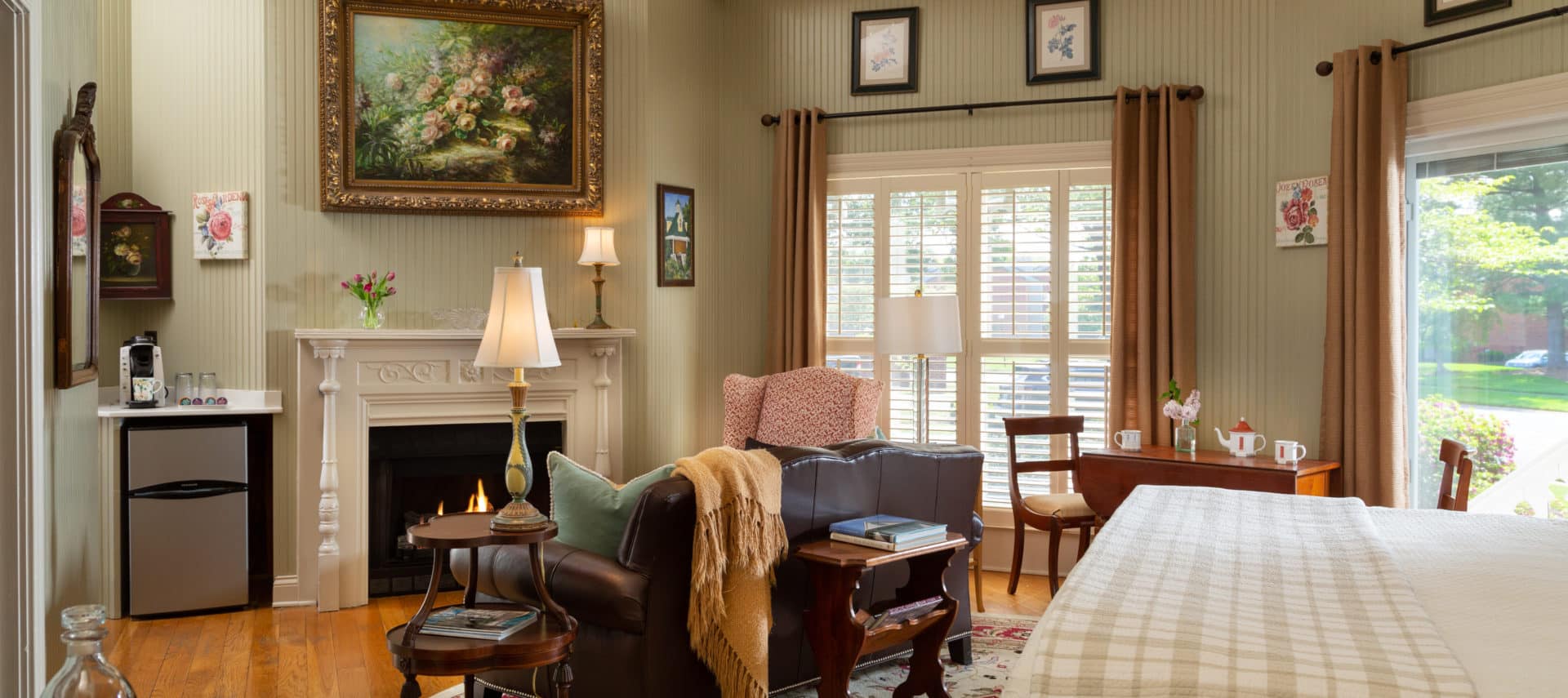 spacious room with pale green walls, a fireplace, leather love seat and ornate lamps.