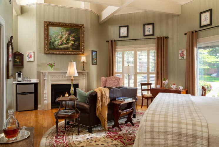 spacious room with pale green walls, a fireplace, leather love seat and ornate lamps.