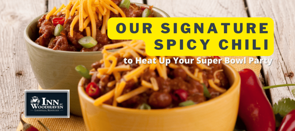 Two bowls of chili topped with yellow shredded cheese and surrounded by red chili peppers on a wooden table, with text that reads "Super Bowl chili recipe" 