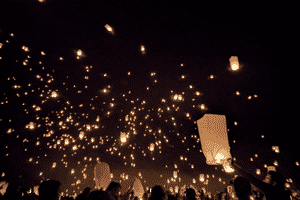 Hundreds of golden chinese lanterns being released into the night sky.
