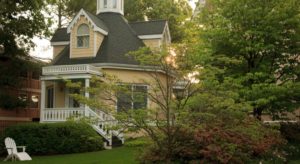 Exterior view of the property painted cream with white trim surrounded by green trees and shrubs