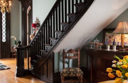Front entry with hardwood flooring, white walls, dark wooden staircase to second floor, and brass chandelier