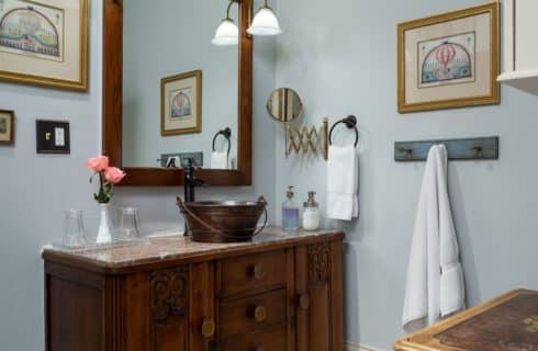 Spacious bathroom area with a large stone-topped vanity and vessel sink. Mirror hangs above the sink and white towels hang alongside the sink on the wall.