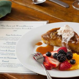 Close up view of white plate with breakfast dish and menu on wooden table