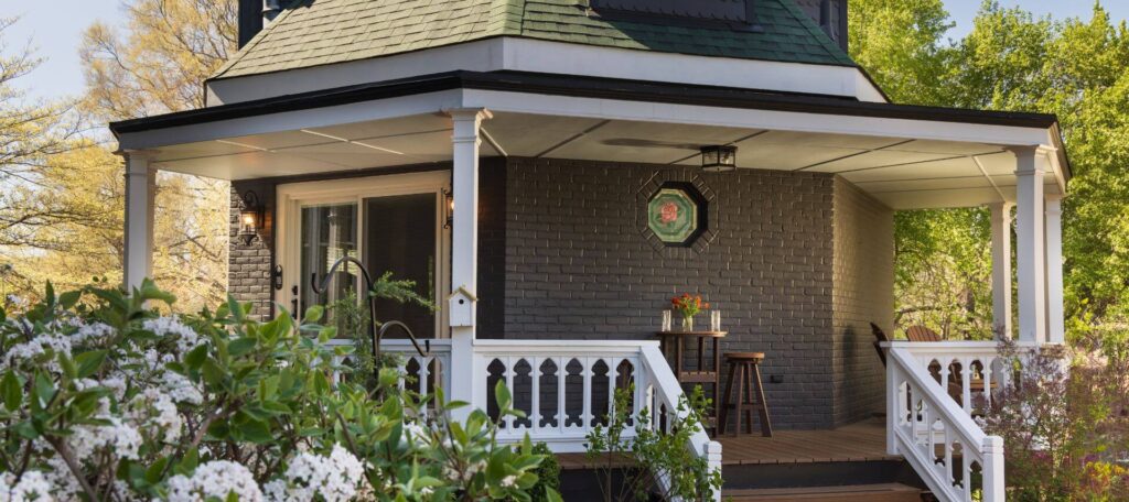 steps up to porch with standing holding refreshments, sliding door into building with stained glass wall on brick wall