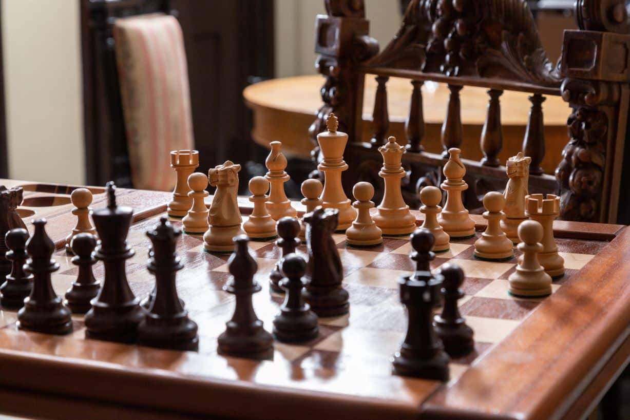 A close up of a wooden handmade game table with a chess game in play.