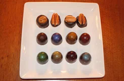 Large square white plate filled with twelve multicolored bourbon and chocolate truffles
