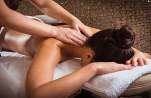 Lady face down on massage table with white towel getting a massage